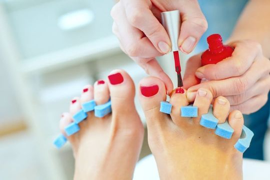 mujer pintando las uñas de los pies de rojo